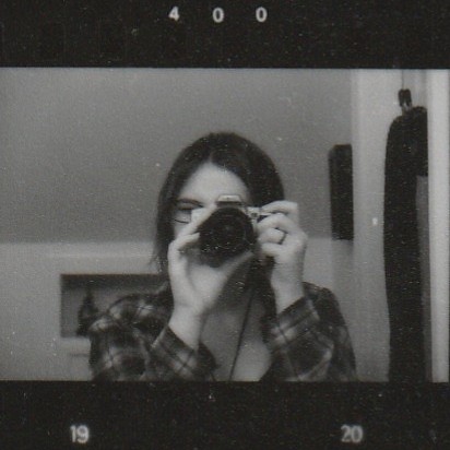 A film photograph of Madison pointing her camera at a mirror, her face covered. From a contact sheet.